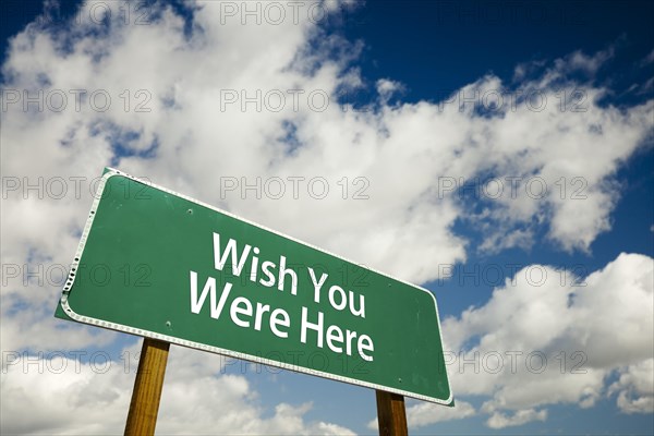 Wish you were here road sign with dramatic clouds and sky