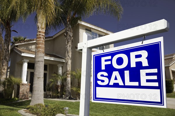 For sale real estate sign in front of house