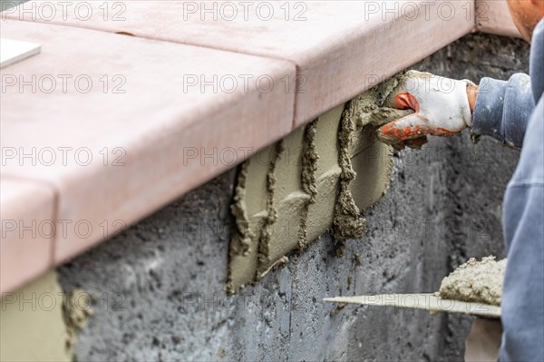 Tile worker applying cement with trowel at pool construction site