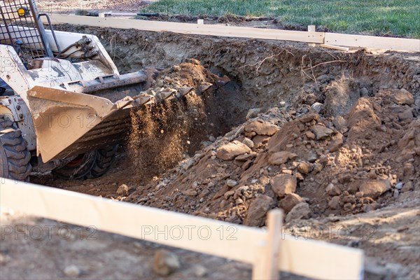 Small bulldozer digging in yard for pool installation