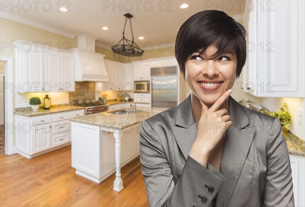 Pretty mixed-race woman looking back over shoulder inside custom kitchen interior