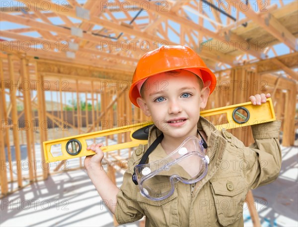 Young boy contractor with level on site inside new home construction framing
