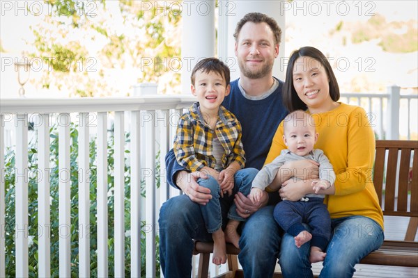 Young mixed-race chinese and caucasian family portrait on their front porch