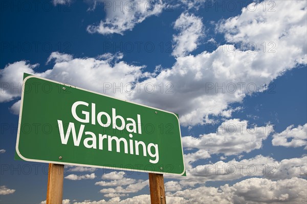 Global warming green road sign over dramatic clouds and sky