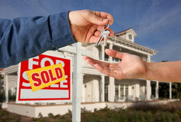 Handing over the house keys in front of a beautiful new home