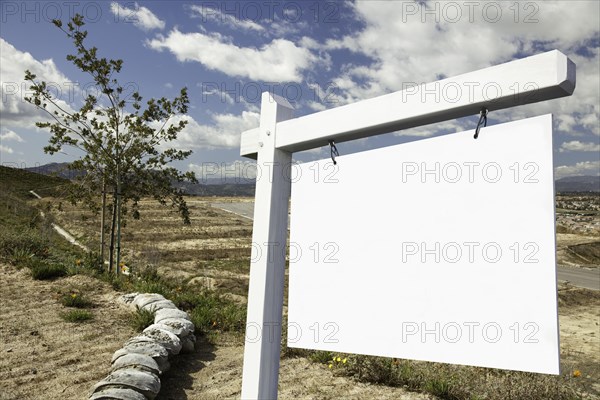Blank real estate sign and empty construction lots