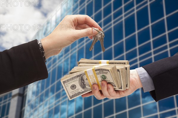 Man handing stack of cash to woman for keys in front of corporate building or apartments