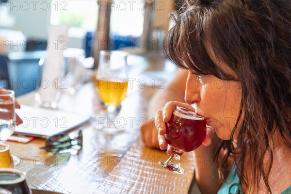 Female sipping glass of micro brew beer at bar with friends