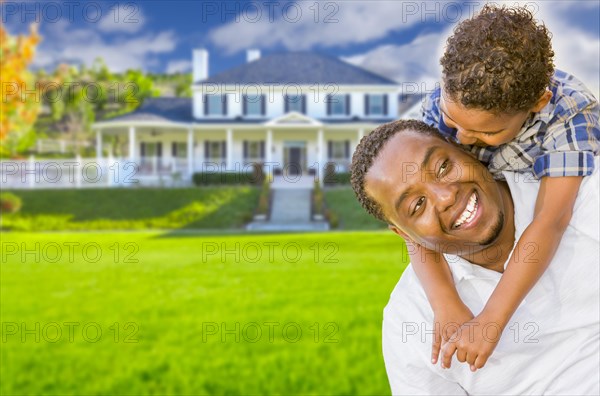 Happy playful african american father and mixed-race son in front of house