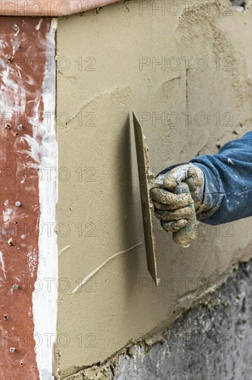 Tile worker applying cement with trowel at pool construction site