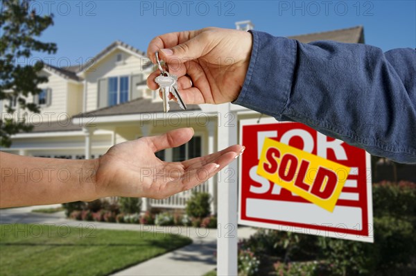 Handing over the house keys in front of a beautiful new home