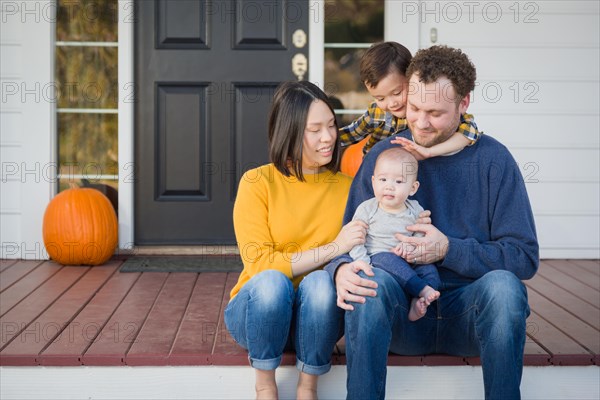 Young mixed-race chinese and caucasian family portrait on their front porch