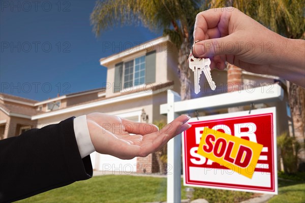 Handing over the house keys in front of a beautiful new home