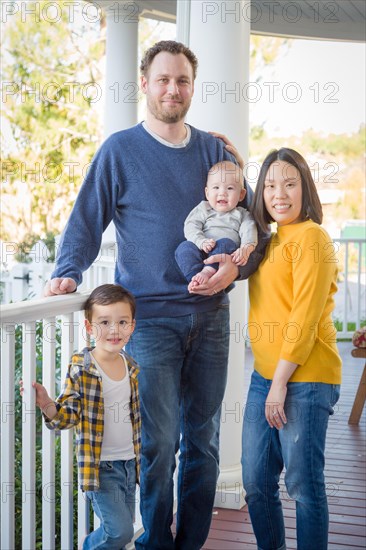 Young mixed-race chinese and caucasian family portrait on their front porch