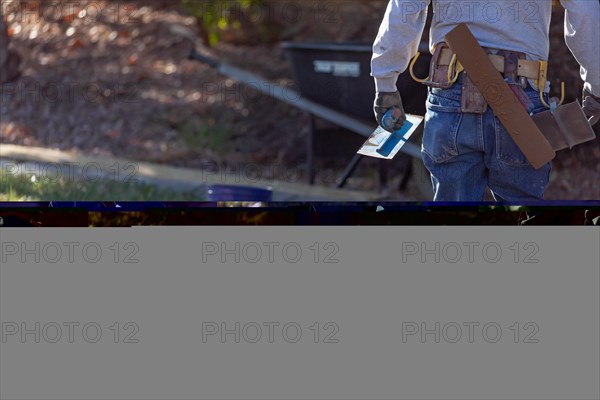 Construction worker with trowel tools near wet deck cement