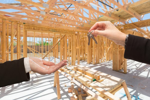 Handing over the keys on site inside new home construction framing
