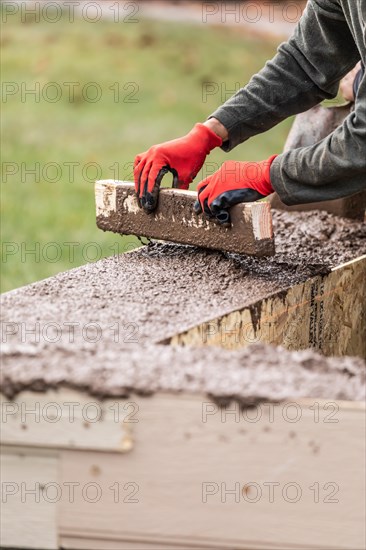 Construction workers pouring and leveling wet cement into wood framing