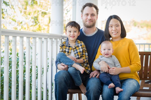 Young mixed-race chinese and caucasian family portrait on their front porch