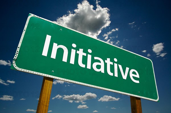 Initiative green road sign over dramatic clouds and sky