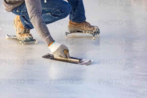 Worker wearing spiked shoes smoothing wet pool plaster with trowel