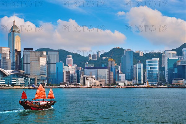 Hong Kong skyline cityscape downtown skyscrapers over Victoria Harbour in the evening with junk tourist ferry boat on sunset with dramatic sky Hong Kong