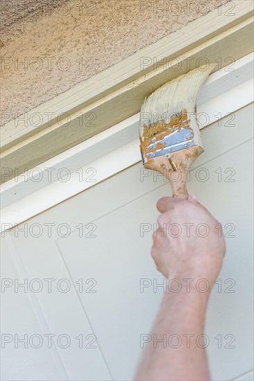 Professional painter cutting in with A brush to paint garage door frame