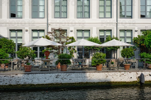 Street cafe restaurant tables with tents along canal in Bruges