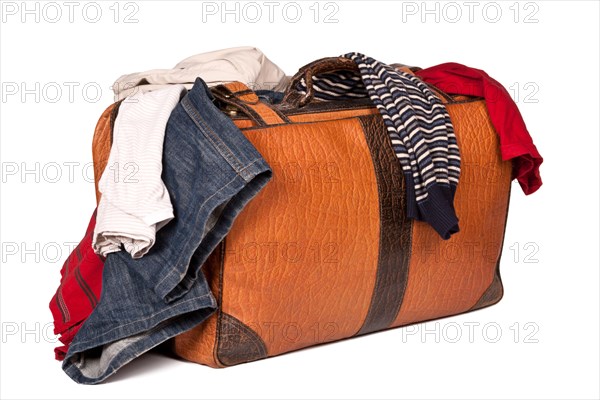 Overstuffed baggage in old suitcase isolated on white background