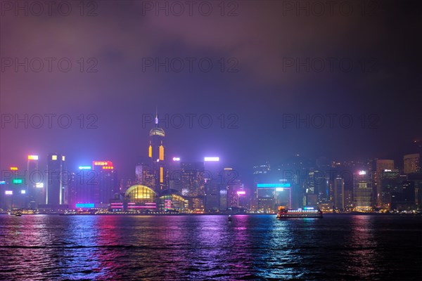 Hong Kong skyline cityscape downtown skyscrapers over Victoria Harbour in the evening illuminated with lasers with tourist boat ferries