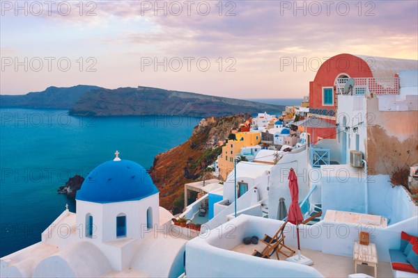 Famous view from viewpoint of Santorini Oia village with blue dome of whitewashed greek orthodox Christian church of traditional greek architecture. Oia town