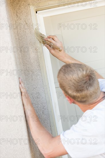 Professional painter cutting in with A brush to paint garage door frame