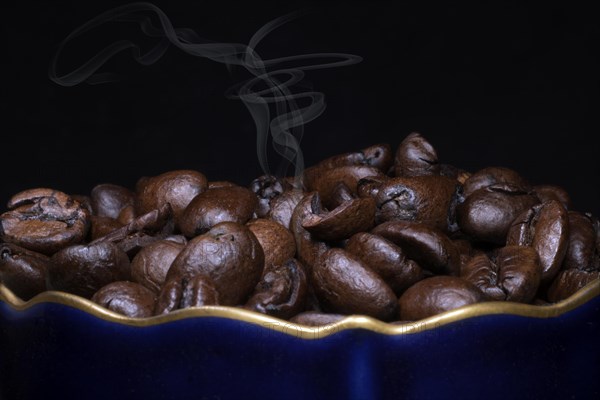 Roasted coffee of the Arabica variety in a porcelain cup in cobalt blue with gold rim