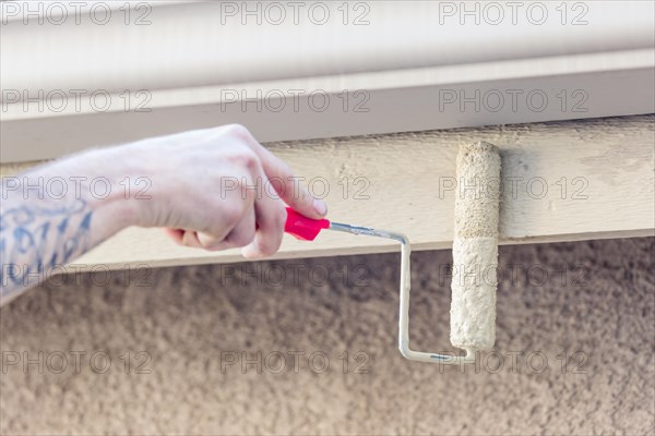 Professional painter using A small roller to paint house fascia
