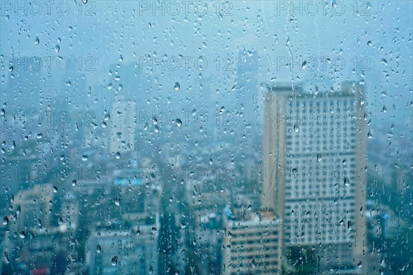 Rain water drops droplets on window glass texture with skyscrapers in background
