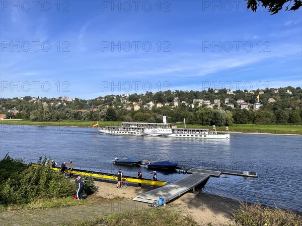 View over a rowing club and boat jetty to the Elbe and a steamer
