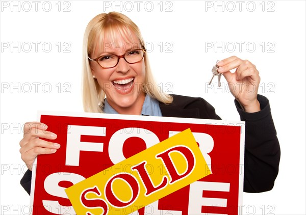 Attractive blonde holding keys & sold for sale sign isolated on a white background