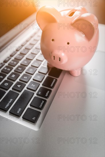 Piggy bank resting on laptop computer keyboard