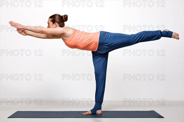 Beautiful sporty fit woman practices yoga asana Virabhadrasana 3