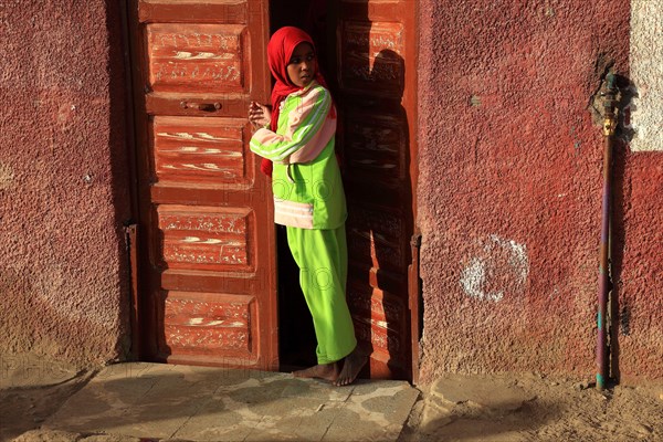 Young girl with headscarf standing in front of the door in a Nubian village in Upper Egypt