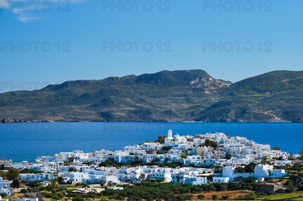 View of Plaka village with traditional Greek orthodox church and white painted houses and ocean coast. Milos island