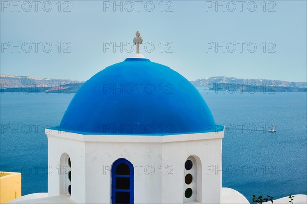 Famous view from viewpoint of Santorini Oia village with blue dome of whitewashed greek orthodox Christian church of traditional greek architecture