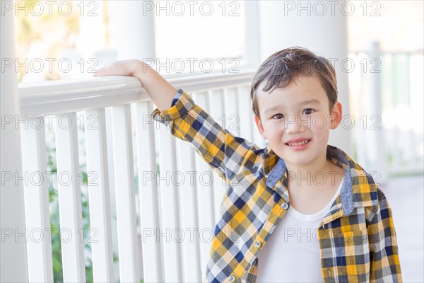 Young mixed-race chinese and caucasian boy on his front porch