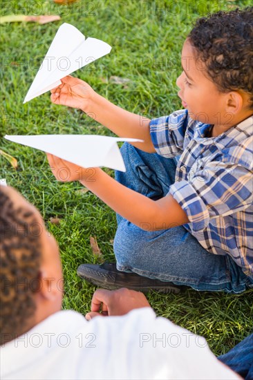 Happy african american father and mixed-race son playing with paper airplanes in the park