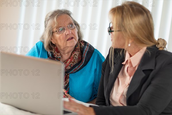 Woman helping senior adult lady on laptop computer
