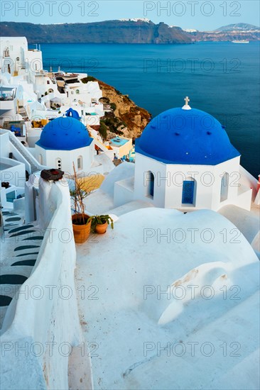 Famous view from viewpoint of Santorini Oia village with blue dome of whitewashed greek orthodox Christian church of traditional greek architecture