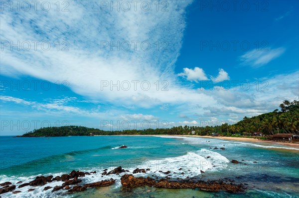 Mirissa beach in Sri Lanka in daytime with clouds and waves in sea