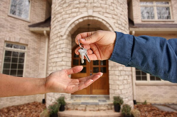 Handing over the house keys in front of a beautiful new home