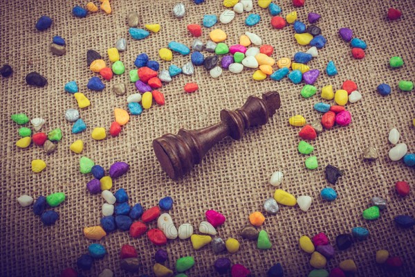 Chess king amid colorful pebbles on canvas background