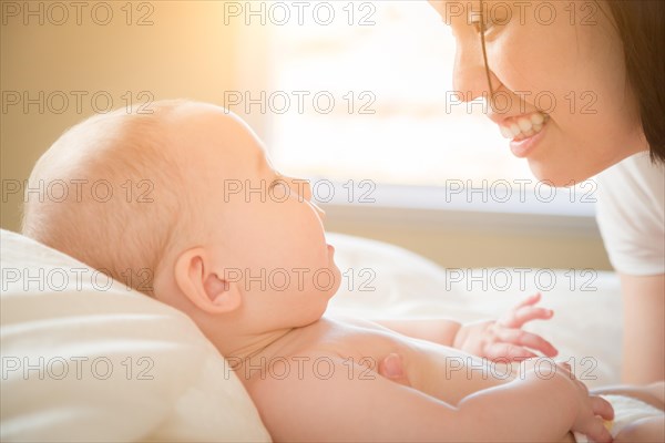 Young mixed-race chinese and caucasian baby boy laying in his bed with his mother
