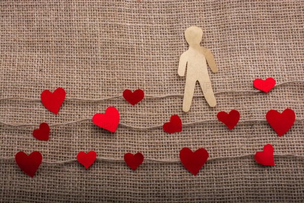 Paper man and heart icons on linen threads on canvas